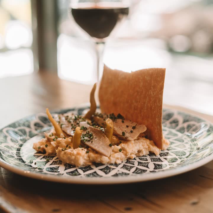Ensaladilla en plato de cerámica con una copa de vino tinto